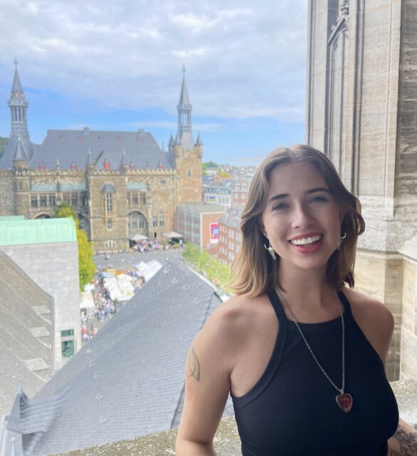 Image of Isabel Smith in front of a large window overlooking the city of Aachen, Germany