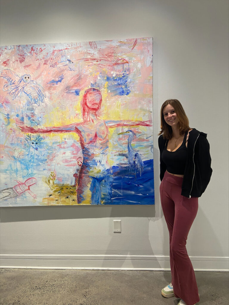 Laura standing in front of their painting, Inner-Child 