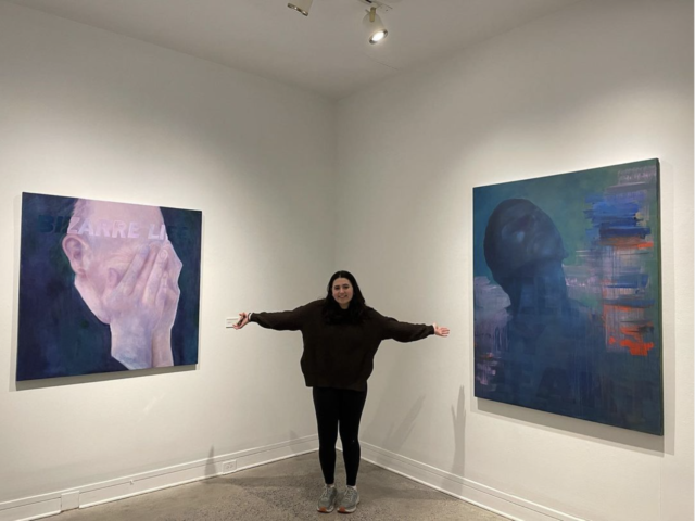 Image of Natalie Hall with her arms open beside two of her works