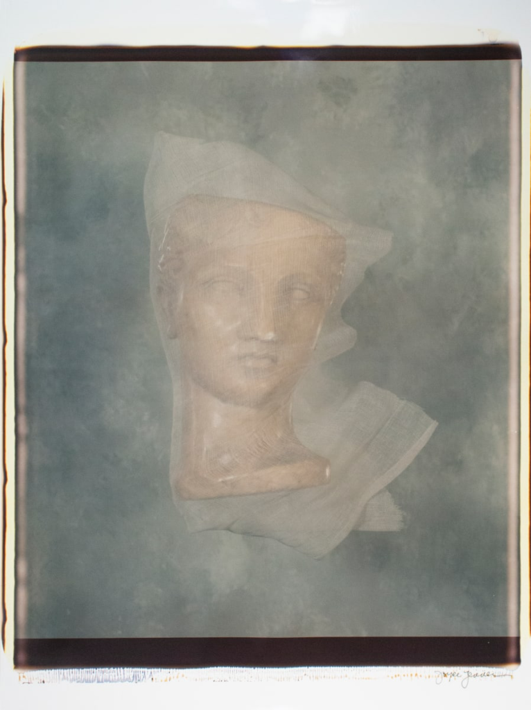Bronze bust wrapped in linen against gray backdrop