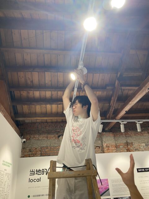 Image of Milk Liu hanging a light