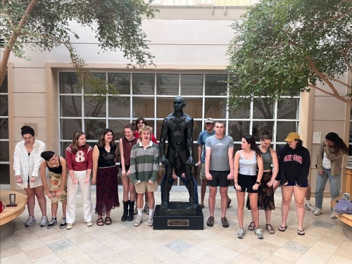 Students standing with a sculpture of a man