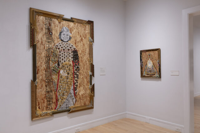 Large mixed-media portrait on plywood with gilded frame fragments, depicting a regal figure adorned with colorful embellishments, hangs on a white gallery wall next to a smaller, similarly styled framed work.