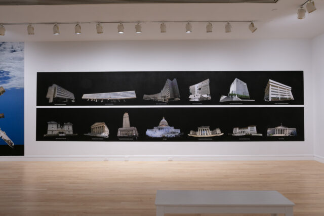 Panoramic black wall display featuring two rows of digitally manipulated architectural images, including modernist and classical buildings, presented as isolated forms on a stark background.