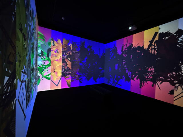 Multi-colored video projection showing plants and architecture.