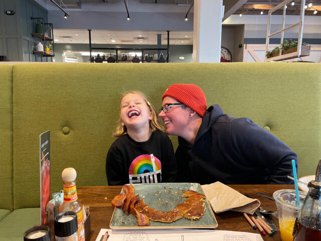 Two people laughing and smiling in a booth at a restaurant, film still from 