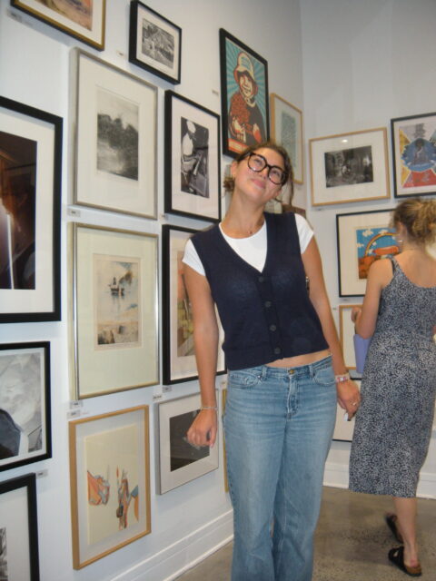 Student with artwork in the gallery